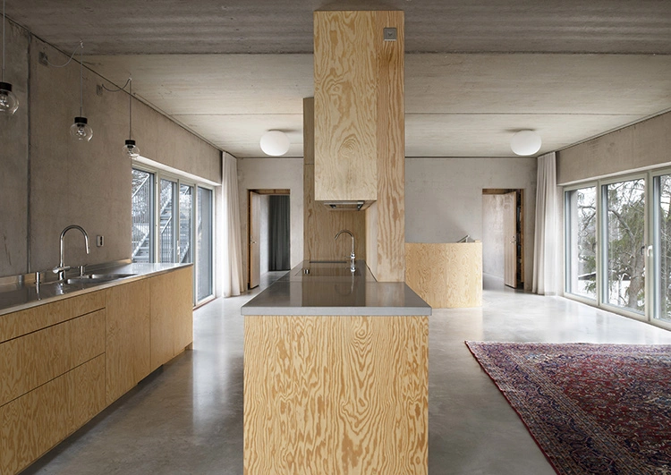 Ở tầng ba, tường, sàn và trần bê tông mịn kết hợp với ván gỗ trong nhà bếp mang đến nét ấm áp tương phản với tường bê tông thô ráp ở bên ngoài