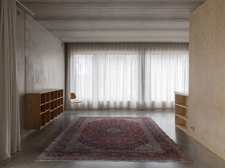 Không gian bên trong ngôi nhà được trang trí theo tông màu trầm với màu xám của bê tông được làm nhẵn cũng như rèm và thảm không quá sặc sỡ